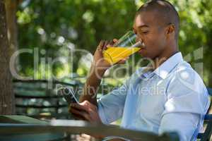Man drinking juice while using mobile phone at restaurant