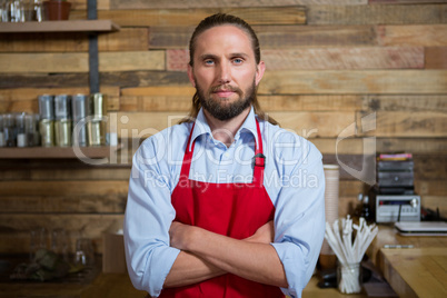 Male barista standing arms crossed in cafeteria