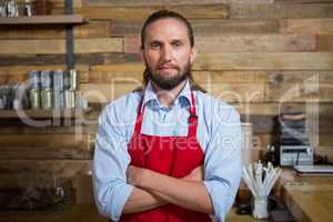 Male barista standing arms crossed in cafeteria