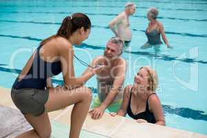 Trainer discussing timing with senior swimmers at poolside