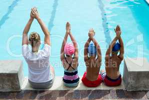 Swimming instructor teaching children at pool side