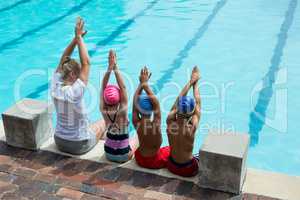 Female swimming instructor with students at pool side