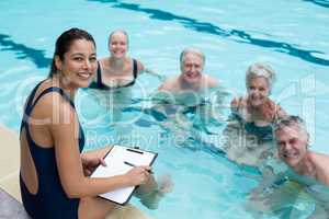 Happy female trainer and senior swimmers