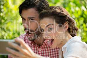 Playful couple taking slefie through mobile phone at park
