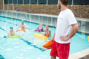 Lifeguard looking at swimmers swimming in pool