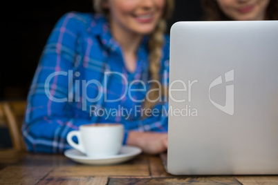 Cropped image of friends using laptop in coffee shop