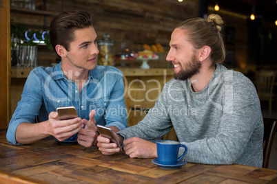 Man talking with friend at table in coffee shop