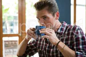 Handsome man drinking coffee in cafeteria
