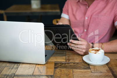 Young man using tablet PC at table in coffee shop Young man using tablet PC at table in coffee shop