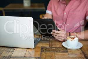 Young man using tablet PC at table in coffee shop