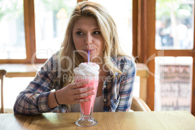 Woman having milkshake at table in coffee shop