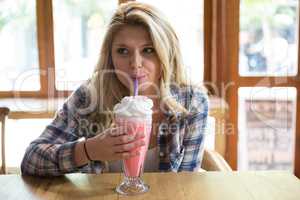 Woman having milkshake at table in coffee shop