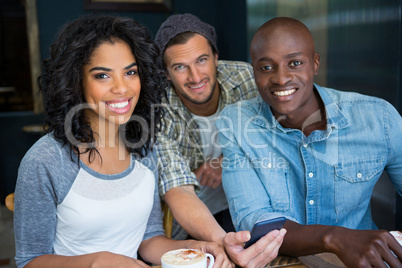 Male and female friends with mobile phone in coffee shop