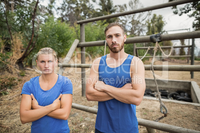 Fit man and woman standing with arms crossed during boot camp training