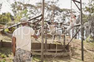 Military soldiers climbing rope during obstacle course training