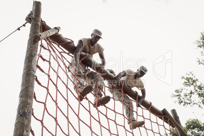 Military soldiers climbing a net during obstacle course