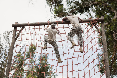 Military soldier climbing a net during obstacle course
