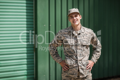 Portrait of smiling military soldier standing with hands on hip
