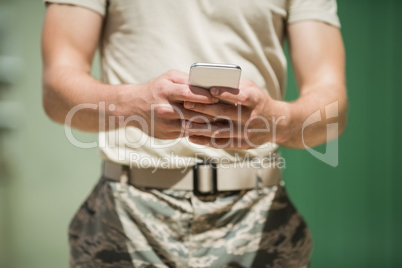 Mid section of military soldier using mobile phone