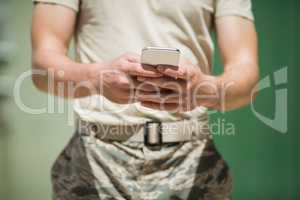 Mid section of military soldier using mobile phone