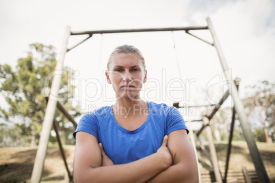 Portrait of fit woman standing with arms crossed during obstacle course