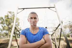 Portrait of fit woman standing with arms crossed during obstacle course