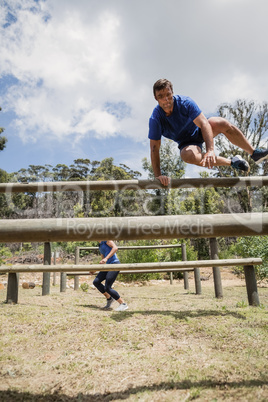 Man and woman jumping over the hurdles during obstacle course