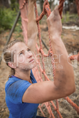 Fit woman climbing a net during obstacle course