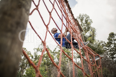 Fit man climbing a net during obstacle course