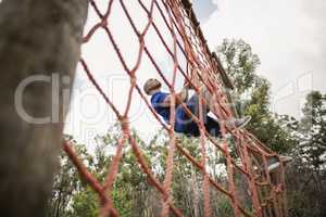 Fit man climbing a net during obstacle course