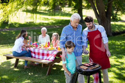 Grandfather, father and son barbequing in the park