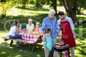 Grandfather, father and son barbequing in the park