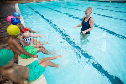 Confident female trainer instructing children in pool