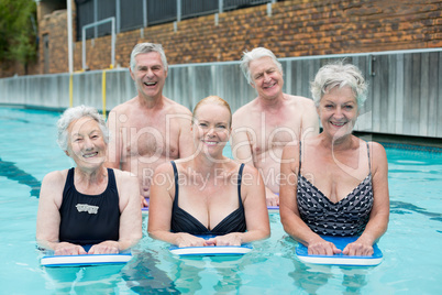 Senior swimmers holding kickboards in swimming pool