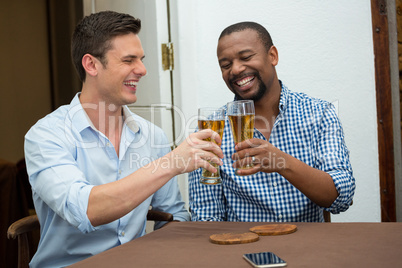 Men toasting beer glasses at restaurant table