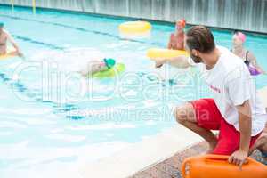lifeguard assisting swimmers at poolside