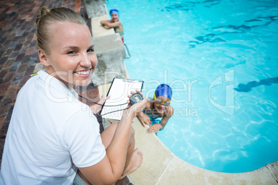 Instructor monitoring time of children swimming in pool