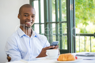 Smiling businessman holding mobile phone in restaurant Smiling businessman holding mobile phone in restaurant