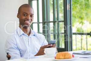 Smiling businessman holding mobile phone in restaurant
