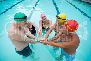 Swimmers stacking hands in pool