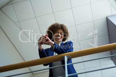 Businesswoman leaning over the railing of staircase