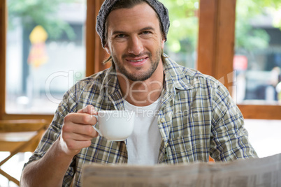 Portrait of smiling man holding coffee cup in cafe