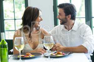 Cheerful couple holding hands at restaurant table