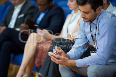 Business executive participating in a business meeting taking notes