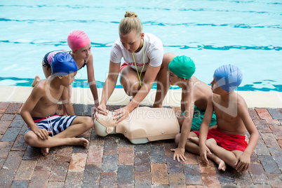 lifeguard giving rescue training to children at poolside