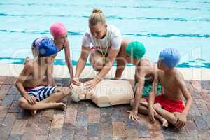 lifeguard giving rescue training to children at poolside