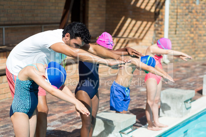 Trainer assisting little swimmers for jumping in swimming pool