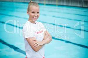 Happy female lifeguard standing at poolside