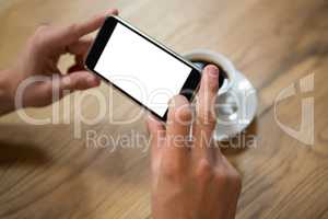 Man hands photographing coffee through smartphone in cafe