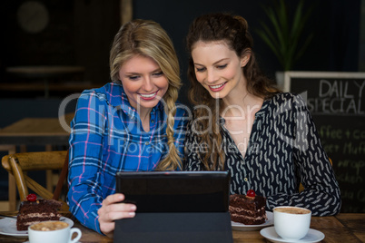 Smiling women using digital tablet in coffee shop